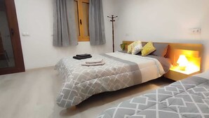 Un dormitorio con dos camas, una lámpara de noche, un perchero y una ventana con cortinas.