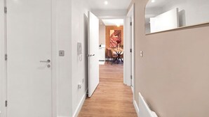 Ein Flur mit einer weißen Tür, ein Essbereich mit Tisch und Stühlen und ein großer Spiegel an der Wand.