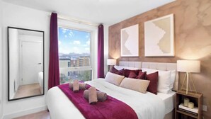 Ein Hotelzimmer mit einem großen Bett, Blick auf die Stadt und zwei gerahmten Karten an der Wand.