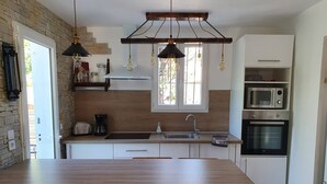 A modern kitchen with a wooden island, built-in appliances, and a hanging light fixture.