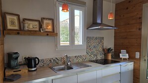 A modern kitchen with a stainless steel sink, wooden cabinets, a built-in oven, and a window with a view of greenery outside. - - (Hyères)