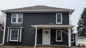 A two-story house with a front porch, a garage, and a number '608' on the side. - Spacious 4-bedroom house in Cherokee with AC (Cherokee)