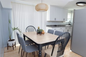 A modern kitchen with white cabinets, a wooden dining table, and grey chairs.