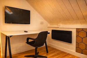 A modern room with a desk, chair, TV, and a hexagonal-patterned wall. - Convenient 3BR Apartment near ExCel, O2 Arena w/Parking, Link to Central London (London)