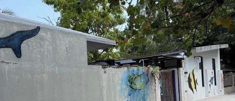 A concrete building with a mural, a door, and a small structure with a roof.