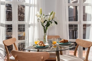 Ein Frühstückstisch mit Croissants, Orangensaft und einer Blumenvase.