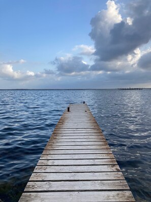 Un muelle de madera que se adentra en aguas tranquilas bajo un cielo parcialmente nublado.