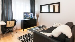 A modern living room with a flat-screen TV, a sofa, a coffee table, and a chair. - Exclusive studio business apartment (Neu-Isenburg)