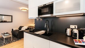 A modern kitchen with a black countertop, stainless steel appliances, and a coffee machine. - Exclusive studio business apartment (Neu-Isenburg)