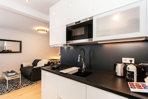 A modern kitchen with a black countertop, stainless steel appliances, and a coffee machine.