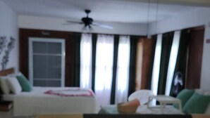 A hotel room with a bed, a sofa, a ceiling fan, and a window with curtains. - Mi Verde Horizonte "Panoramic view in Utuado | Nearby river + Nature + WiFi". (Utuado)