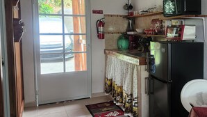 A kitchen with a refrigerator, microwave, and a coffee machine. There is a door with a 'SALIDA' sign and a fire extinguisher on the wall. - Mi Verde Horizonte "Panoramic view in Utuado | Nearby river + Nature + WiFi". (Utuado)