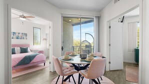 Een moderne kamer met een bed, een eettafel met stoelen en een glazen schuifdeur naar een balkon.