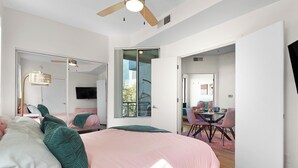 Een slaapkamer met een groot bed, een plafondventilator en een schuifdeur naar een balkon.