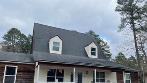 A two-story house with a dark shingled roof, a front porch with white railings, and a small attached garage. - Spacious 4-bedroom house in Augusta about 22 min from Augusta National Golf Club (Augusta)