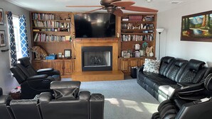 A living room with a fireplace, bookshelves, a television, and leather sofas. - Spacious 4-bedroom house in Augusta about 22 min from Augusta National Golf Club (Augusta)