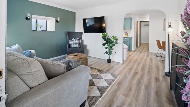 Ein modernes Wohnzimmer mit einer Couch, einem Fernseher und einer Pflanze.