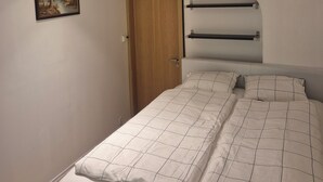 Ein Schlafzimmer mit Bett, Tür, Ablagefläche und einem Bild an der Wand.