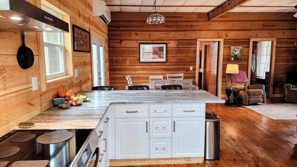 A wooden interior with a kitchen area, dining table, and seating.