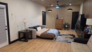 A modern living room with a sofa, a bed, a coffee table, and a TV stand. - Beamsville Modern Rustic Suites (Lincoln)