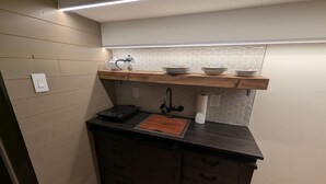 A compact kitchen with a wooden countertop, a built-in stove, a sink, and a hexagonal backsplash. - Beamsville Modern Rustic Suites (Lincoln)