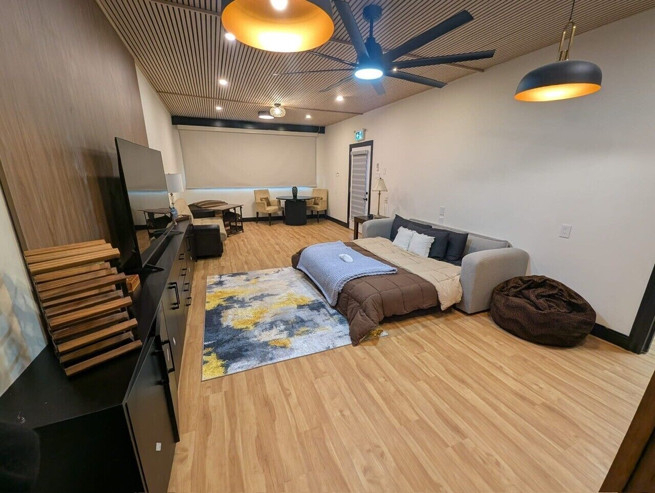 Un salon moderne avec un canapé, une table basse, un téléviseur et un ventilateur de plafond.