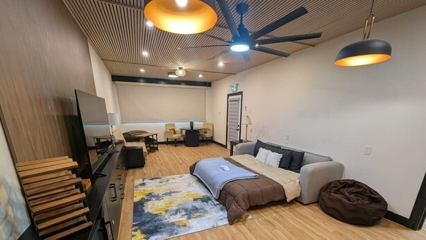 Una sala de estar moderna con un sofá, una mesa de centro, un televisor y un ventilador de techo.