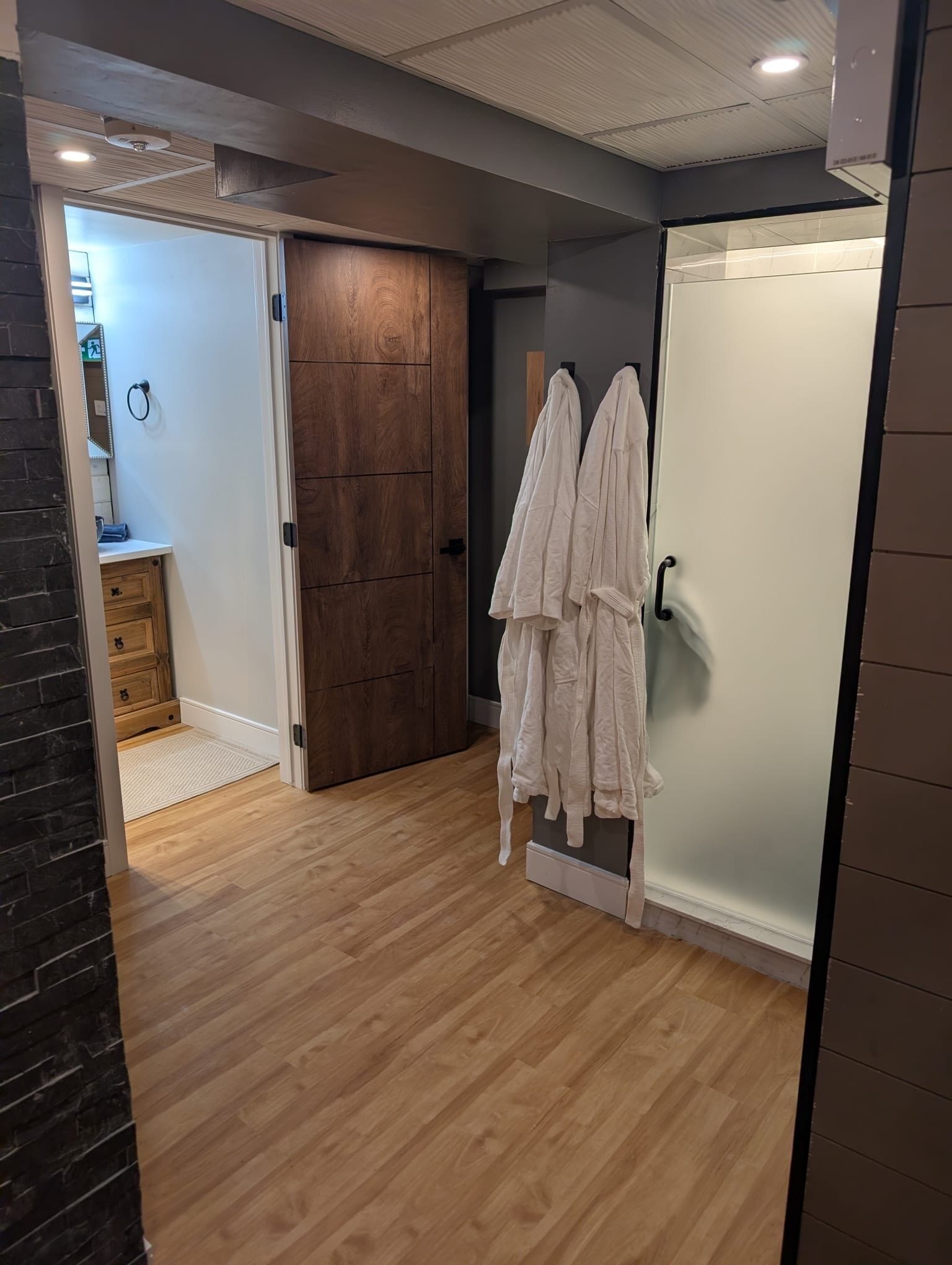 A bathroom with wooden flooring, a white sink, and a towel rack with white towels.