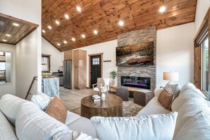 A spacious living room with a stone fireplace, wooden ceiling, and a cozy seating area. - Free Dollywood Tickets, Luxurious, Modern, A+Location, Fire Pit (Sevierville)