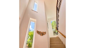 A staircase with a handrail and a view of greenery outside. - Casa da Madrugada - Peaceful haven with pool and ocean view in Salema (Salema)