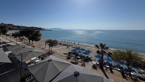 Une vue sur la plage, avec des parasols, des chaises et un ciel dégagé.