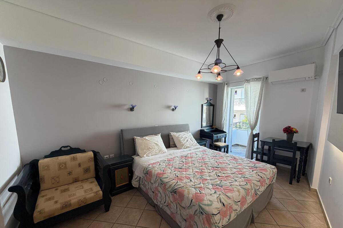 A bedroom with a bed, bedside table, chair, dresser, and a ceiling light fixture.