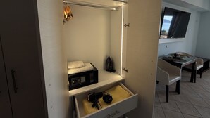 Une chambre d’hôtel comprenant un lit, un bureau avec une chaise, une télévision et une armoire avec une tringle pour suspendre les vêtements.