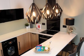 Eine moderne Küche mit eingebauter Waschmaschine, einem Essbereich mit weißem Tisch und einer dekorativen Lampe.