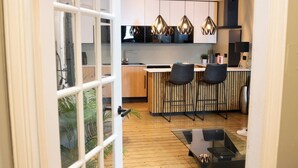 A modern kitchen with wooden cabinets, a black countertop, and two black chairs. - Urban One Central Location (Aberdeen)
