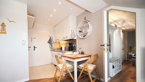 Una cucina funzionale con un tavolo e sedie in legno, una macchina per il caffè e una lampada a sospensione.
