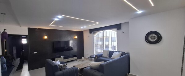 Una sala de estar moderna con un televisor de pantalla plana, un sofá, una mesa de centro y un ventanal con vistas.