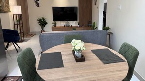 Un'area pranzo moderna con un tavolo rotondo, sedie rivestite in verde e un vaso centrale con fiori bianchi.