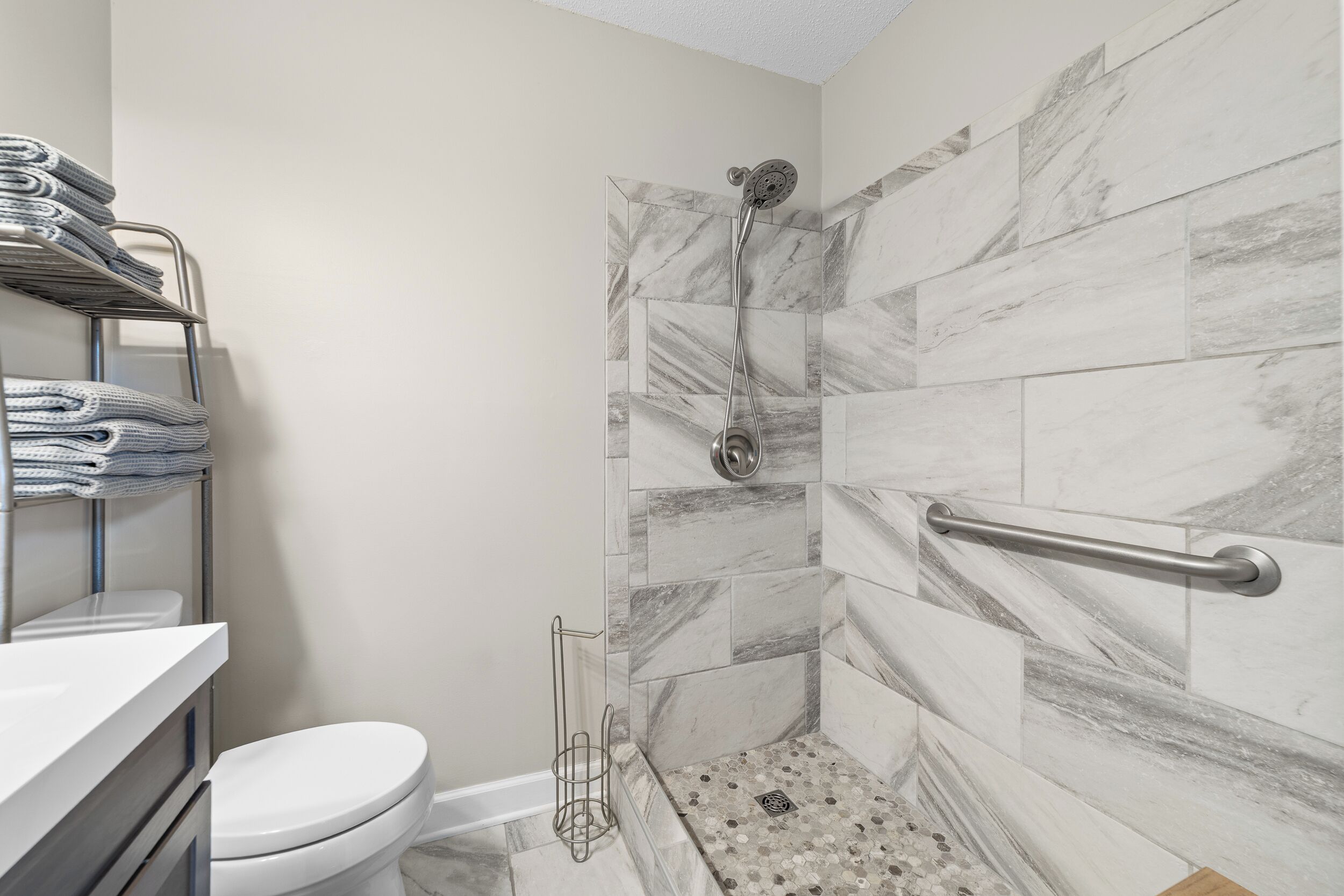 A bathroom with a shower, toilet, and towel rack.