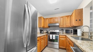 A modern kitchen with stainless steel appliances, wooden cabinets, granite countertops, and a stainless steel sink. - Tuscany Lane Townhouse - 2 floors, Near Lake, Pool, Pets OK - LKN Location (Cornelius)