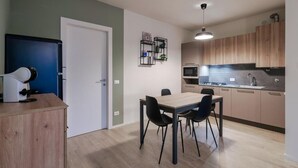 Eine moderne Küche mit Holzausstattung, integriertem Mikrowellenherd und Spüle. Ein Essbereich mit Tisch und Stühlen ist ebenfalls vorhanden.