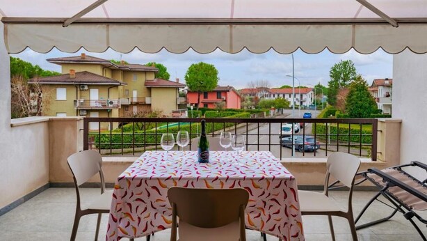 Ein Balkon mit Tisch für zwei Personen, einer Weinflasche und zwei Gläsern.