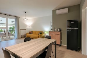 A compact living space with a dining area, a sofa, a kitchenette, and a sliding glass door leading to an outdoor area. - Attilia House. Brand new one bedroom apartment for your unforgettable vacation in Sirmione (Sirmione)