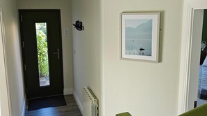Un pasillo con una puerta que da a una habitación, un radiador y un cuadro en la pared.