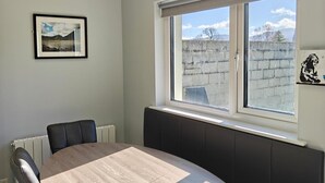Una habitación con un gran ventanal, un cuadro enmarcado en la pared y una mesa con sillas.