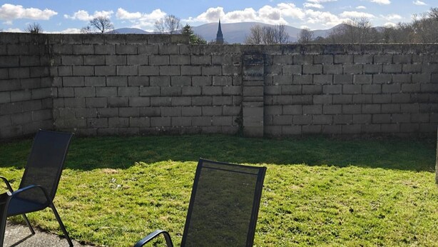 Un muro de ladrillo con un área verde al frente.