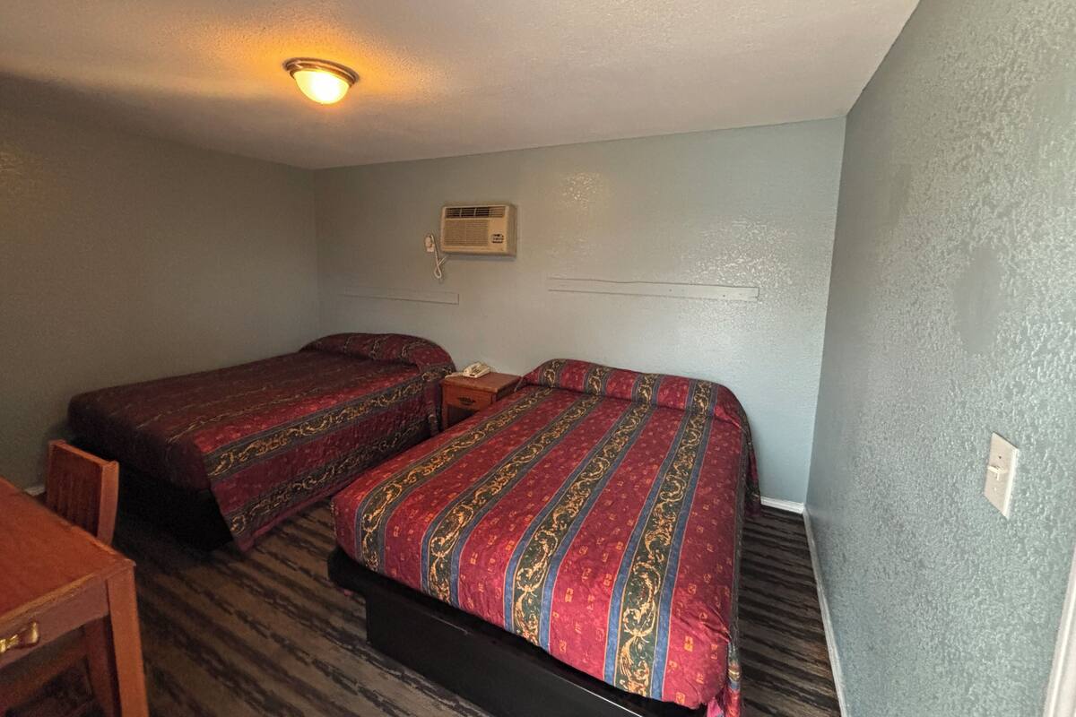 A room with two beds, a desk, and a ceiling light.