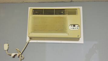 Un climatiseur ancien, doté d’un panneau de commande et relié à une prise électrique murale.