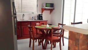 Una cocina moderna con zona de comedor, refrigerador, microondas y cafetera.