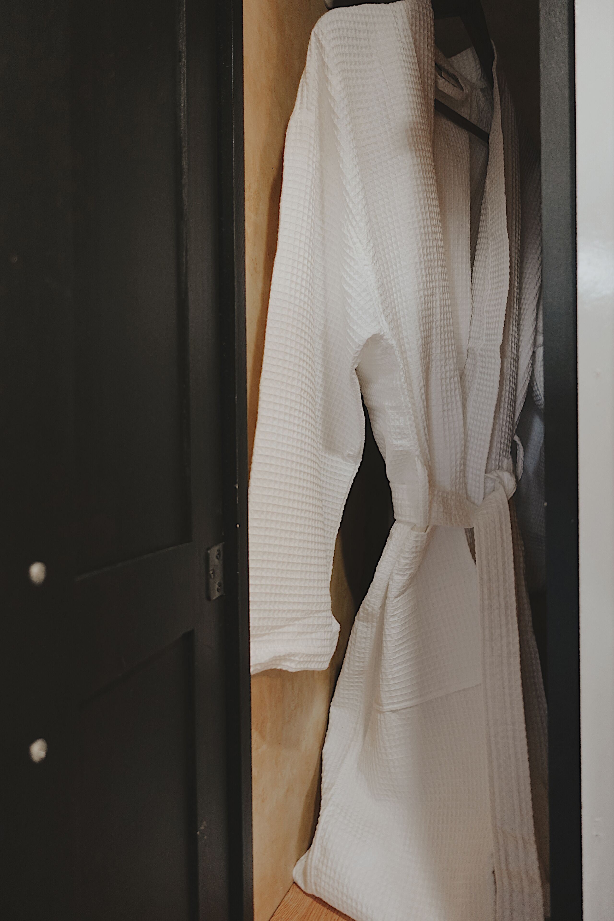 A white robe hanging on a wooden door.